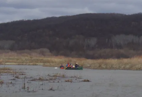 Two canoes with people in them float on a river
