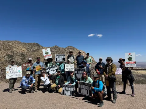 a group of anti-borderwall protestors on a desert mountain