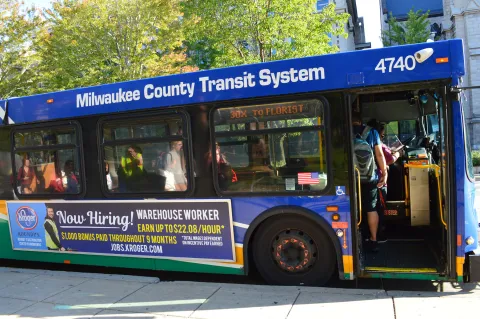 Picture of a Milwaukee bus with people getting on at a stop