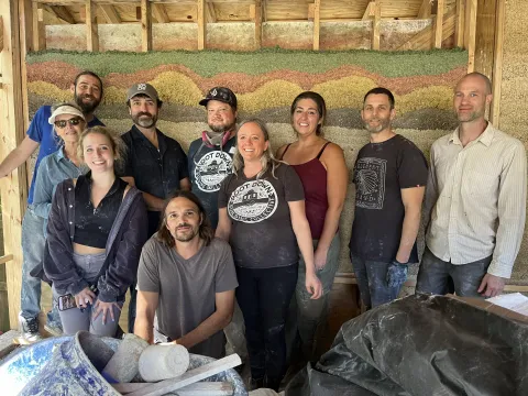 A group of peeple standing in front of a hemp-crete wall