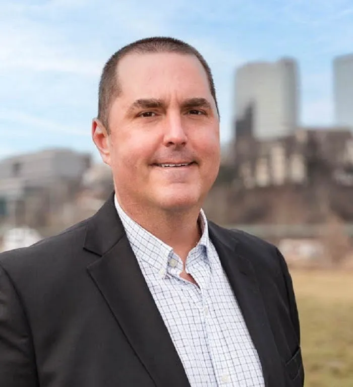 Cameron Brooks, a white man with short dark hair, poses in front of a cityscape.