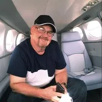 white man wearing glasses in black T-shirt and black seed cap