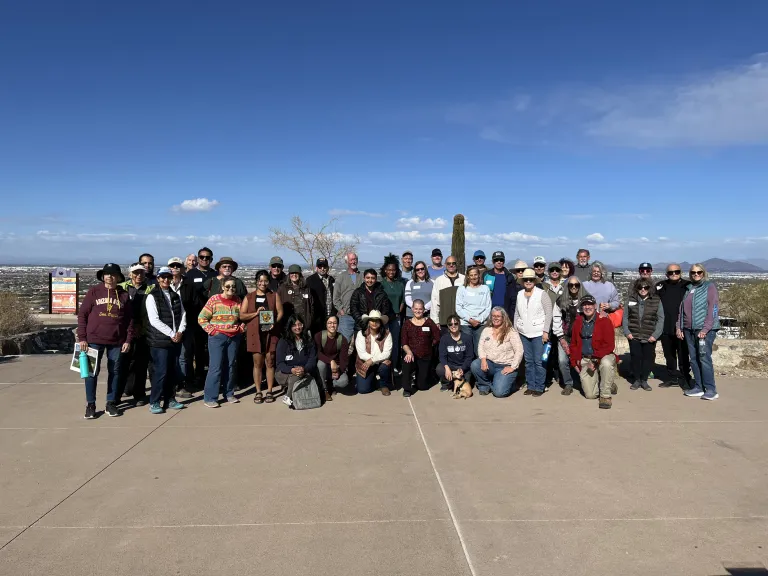 A group of people posing for a photo with the city of Phoenix in the background