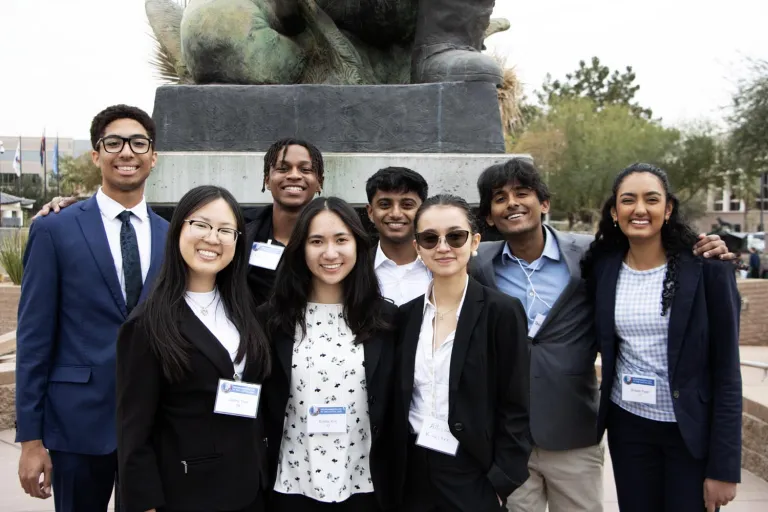 a group of young people poses next to a statue