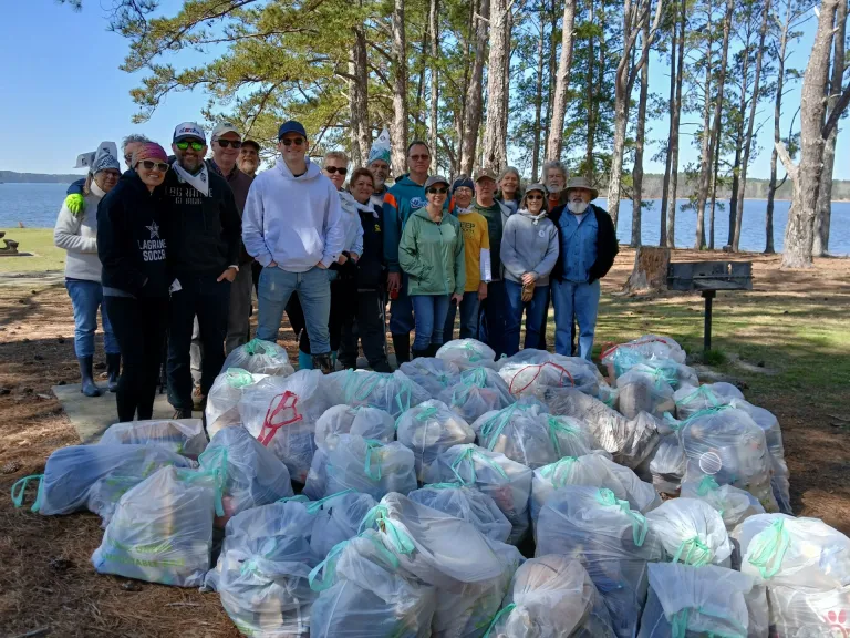 Volunteers stand with piles of full trash bags representing the garbage they pulled from the Chattahoochee