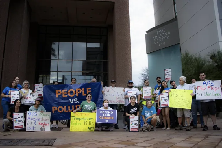 a group of protestors holdling signs in front of APS building