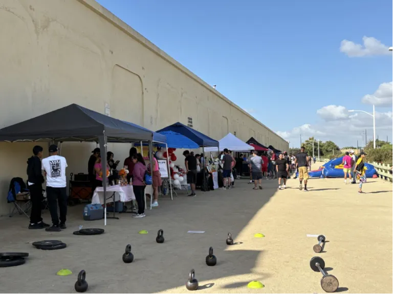Row of stands with umbrellas, including many dumbbells on the ground