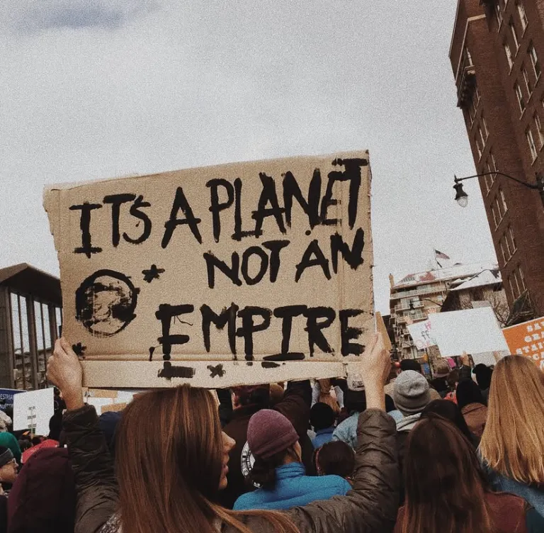 Protestors holding sign that reads "It's a planet not an empire"