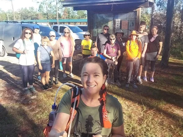 Group photo of individuals on a local hike, with Carla in front of the group posing for the photo