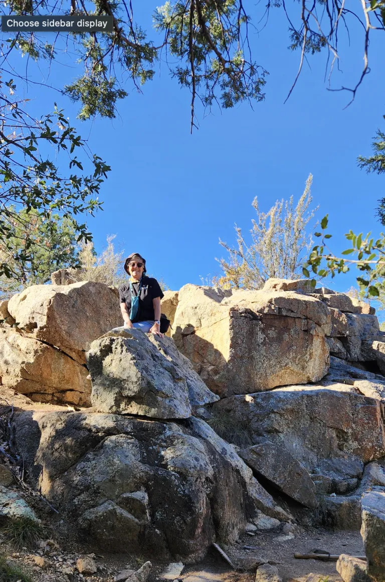 a person poking out behind some large boulders in a rocky area