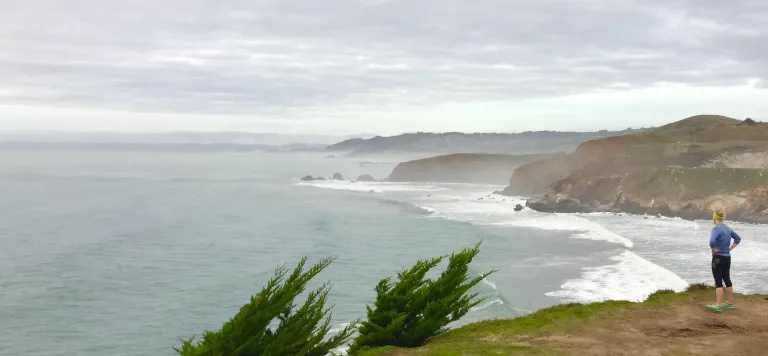 Woman looking out over ocean, grey skies
