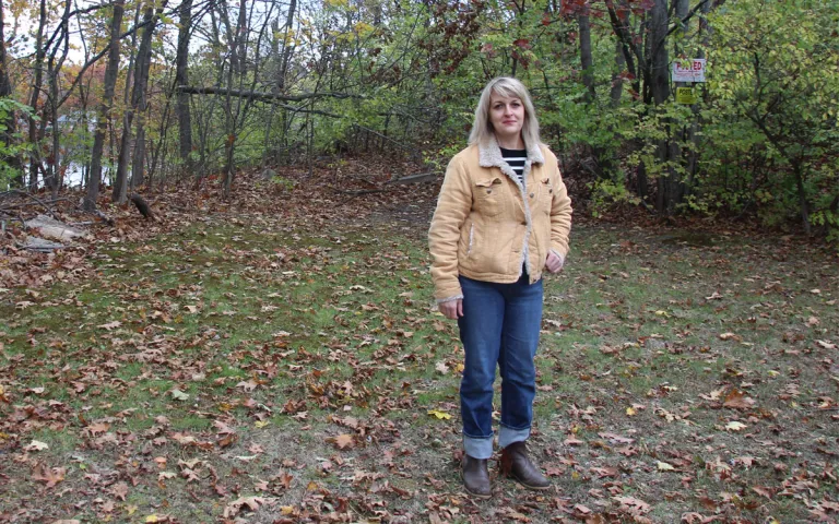 Jess Bennett stands in her backyard in front of a “Posted: Private Property” sign marking the property line of the 1011 2nd Avenue Forest. The Hudson River is behind her.