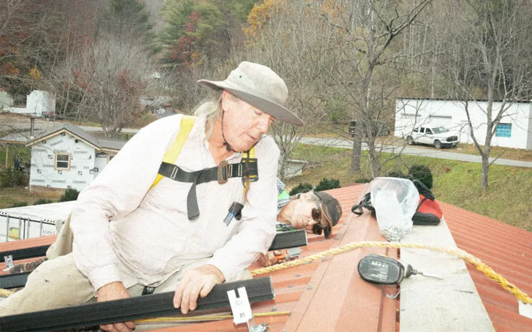 Volunteers mount solar panels on the fire department's roof. 