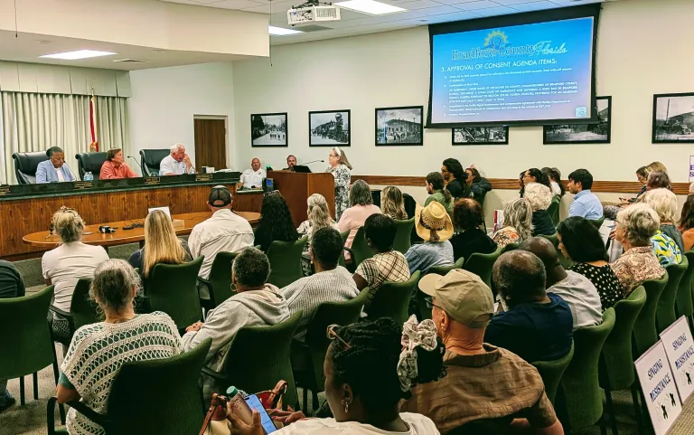 Bradford County Commissioners listening as resident speaks at the podium in a roomful of local residents listen while seated