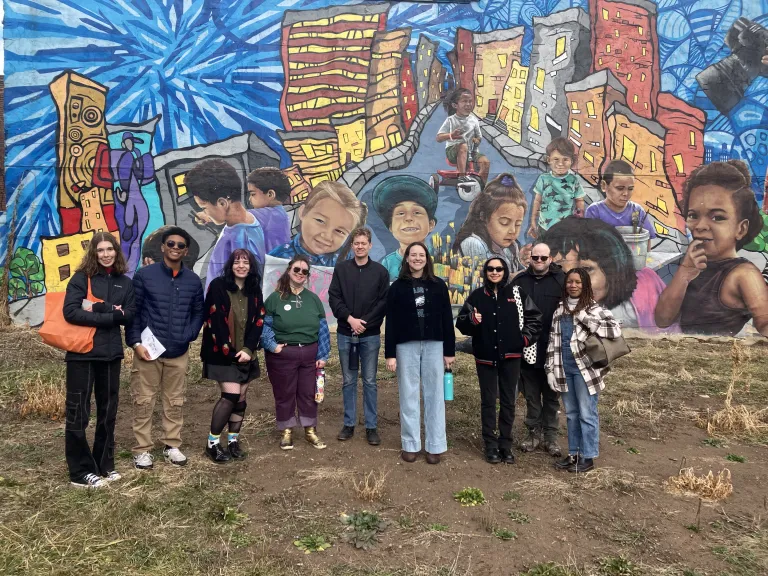 Attendees pose in front of a mural during Sierra Club's tour of the Kensington Community Gardens.