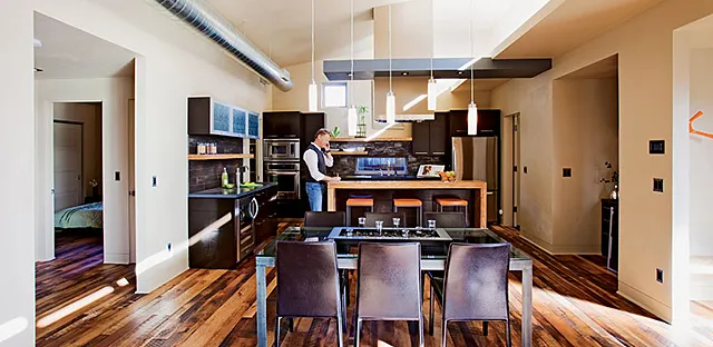A "light shelf" reflects natural light from high windows deep into the house, showcasing reclaimed-lumber flooring.