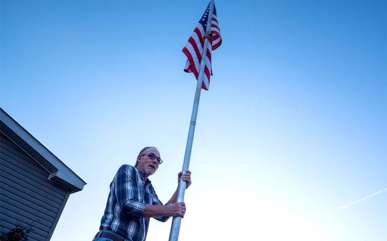Leo DeMi raises the American flag in his front yard as the sun dips behind the hills of Berwick, Pa. on Sept. 15, 2026.