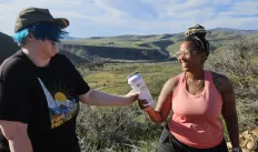 2 people smiling at each other and reaching for water bottle