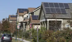 picture of multiple houses with rooftop solar on top on a street