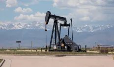 An oil pump jack with mountains sprawling in the background 