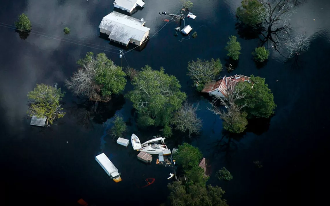 Overhead photo shows houses almost completely submerged in water, treetops, and floating items.