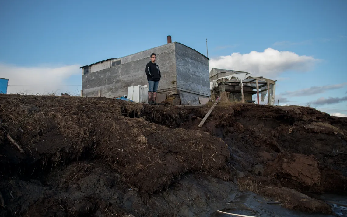 Katie Ayuluk stands at the coastline near where her home used to be.