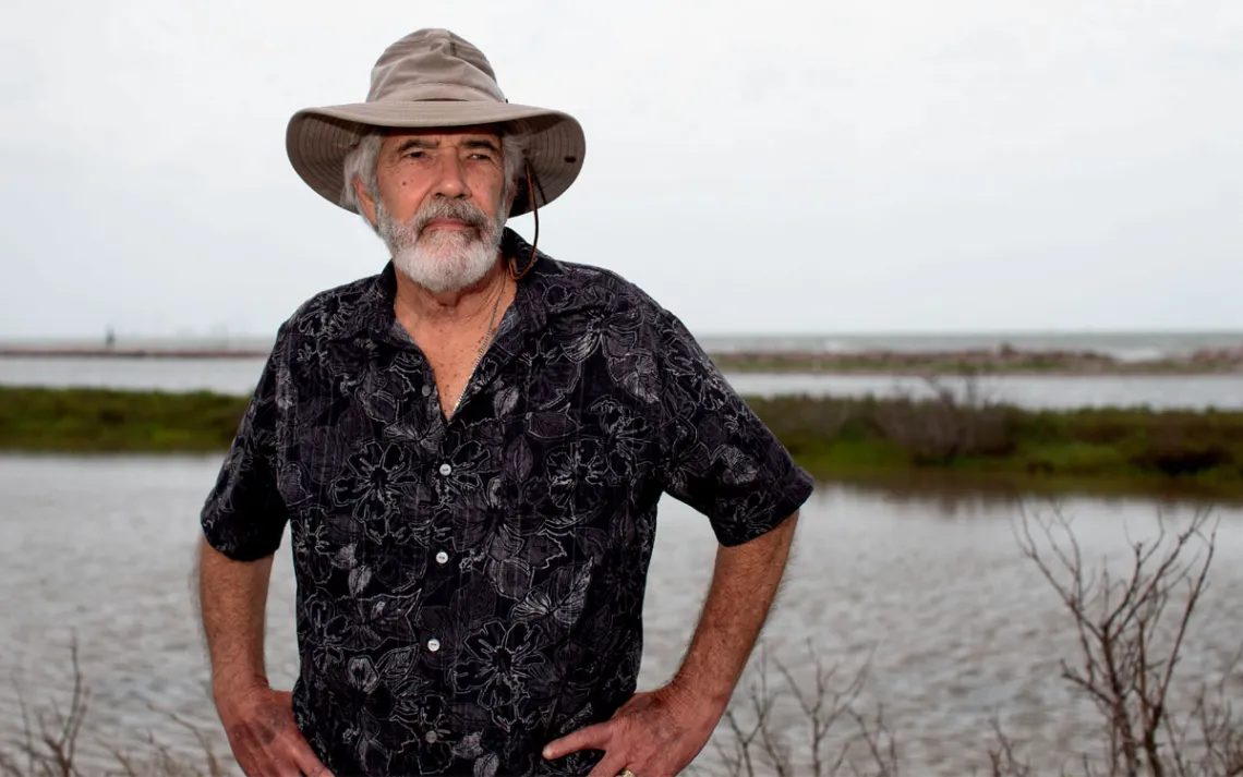 Errol Summerlin wears a black button-up shirt and wide-brimmed hat and has his hands on his hips.