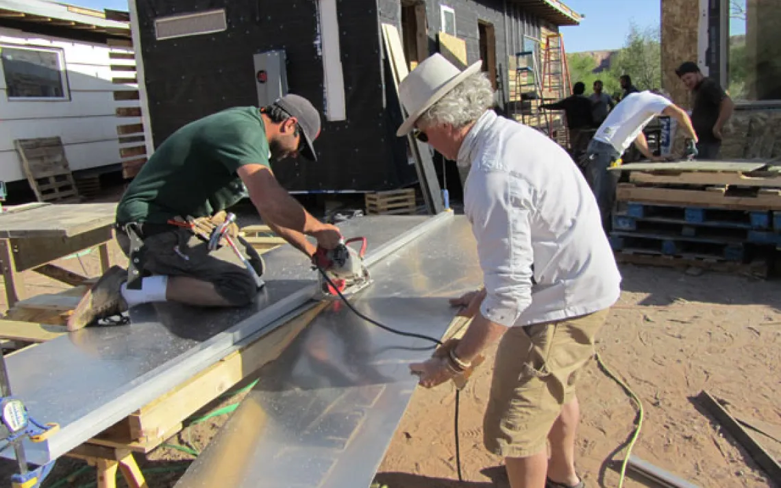 Louis helps a student cut a sheet of aluminum.