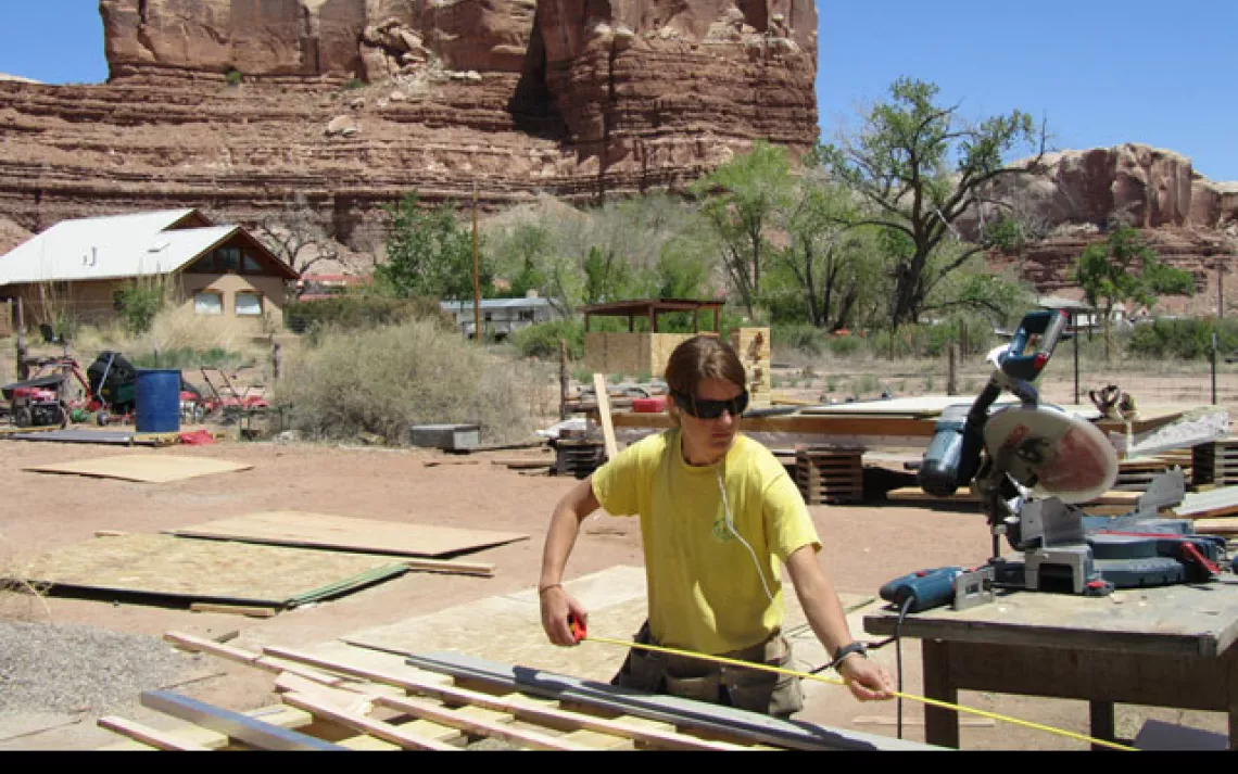 A student measures lumber at the DesignBuildBluff compound in Bluff, Utah.