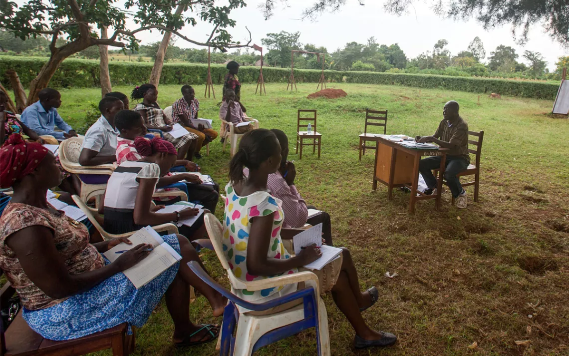 Stephen Okollet teaches an accounting class to a group of volunteers in Uganda.