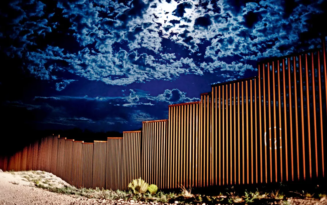 The U.S.-Mexico border fence highlighted by Border Patrol headlights in Sasabe, Arizona.