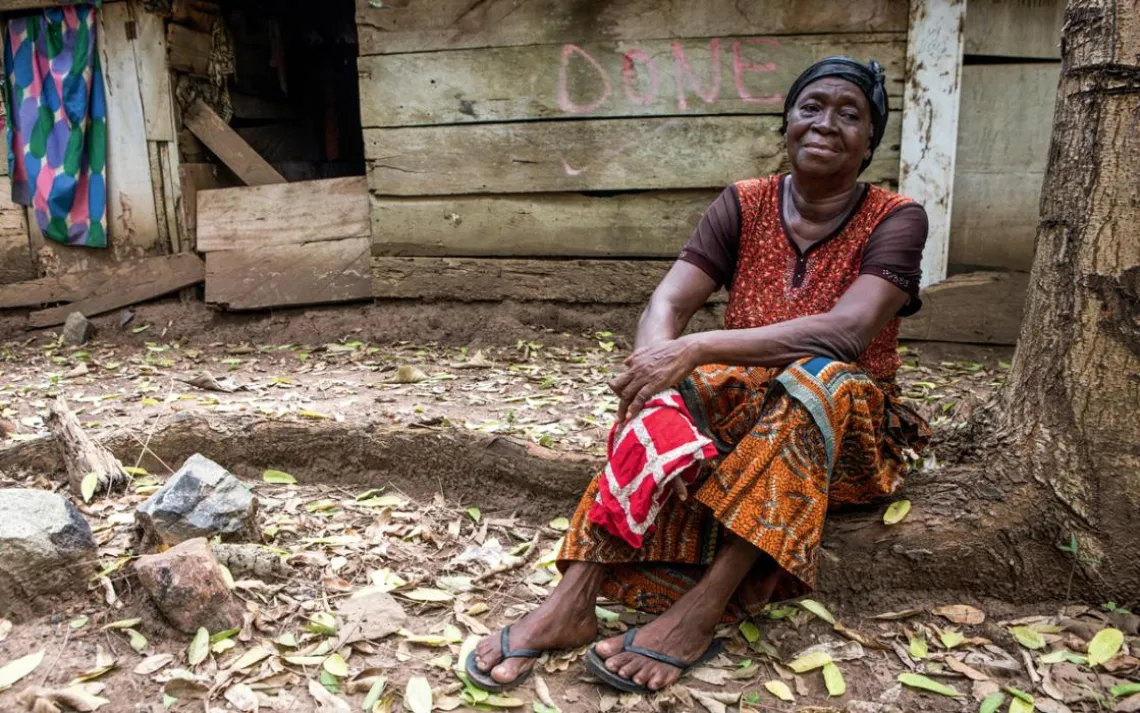 Yaa Konadu sits outside the farmhouse in Ghana that Newmont took away from her. Company workers spray-painted "Done" on the wall.