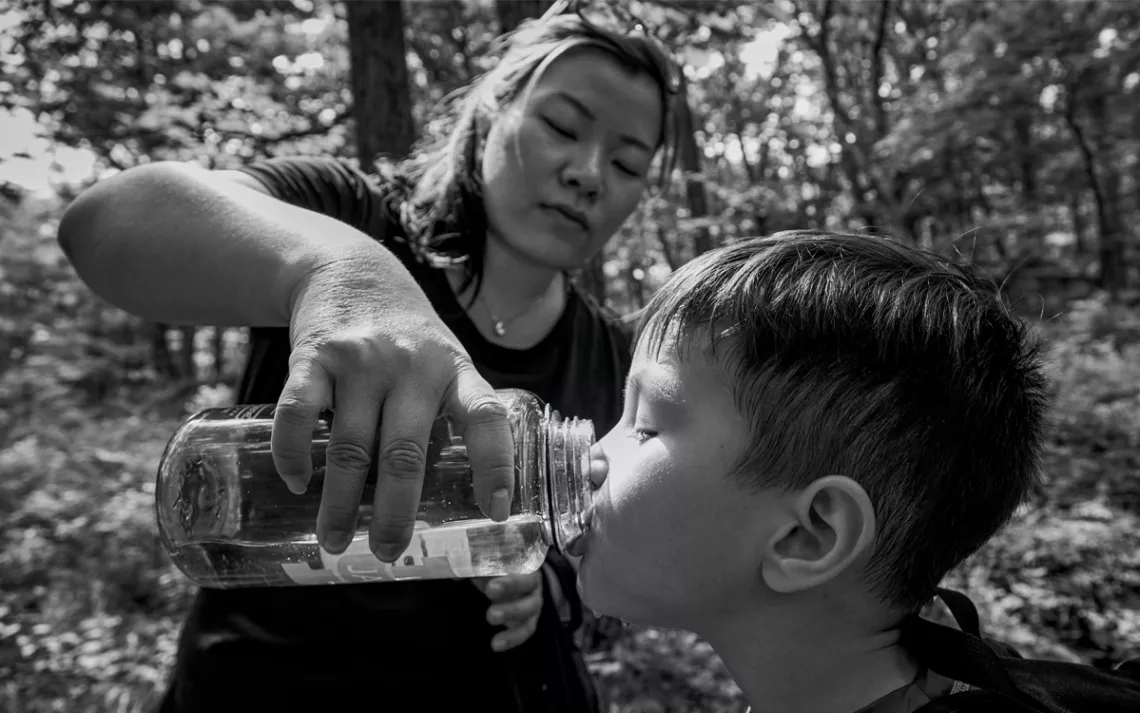 Sherry and Elijah share water on the trail.