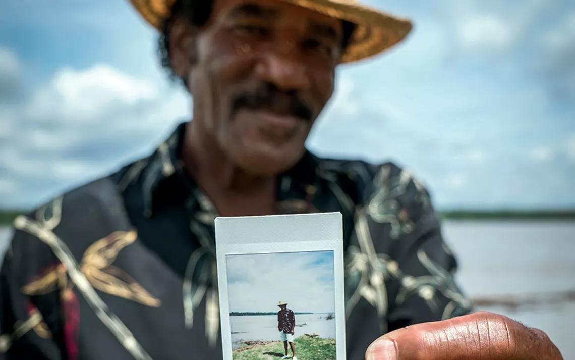 Veteran Quapaw Canoe Company driver Ellis Coleman holds up a Polaroid of himself at Terrene Landing in Bolivar County, Mississippi.