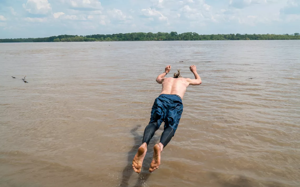 Quapaw Canoe Company founder John Ruskey is about to land in the Mississippi River face down after jumping.