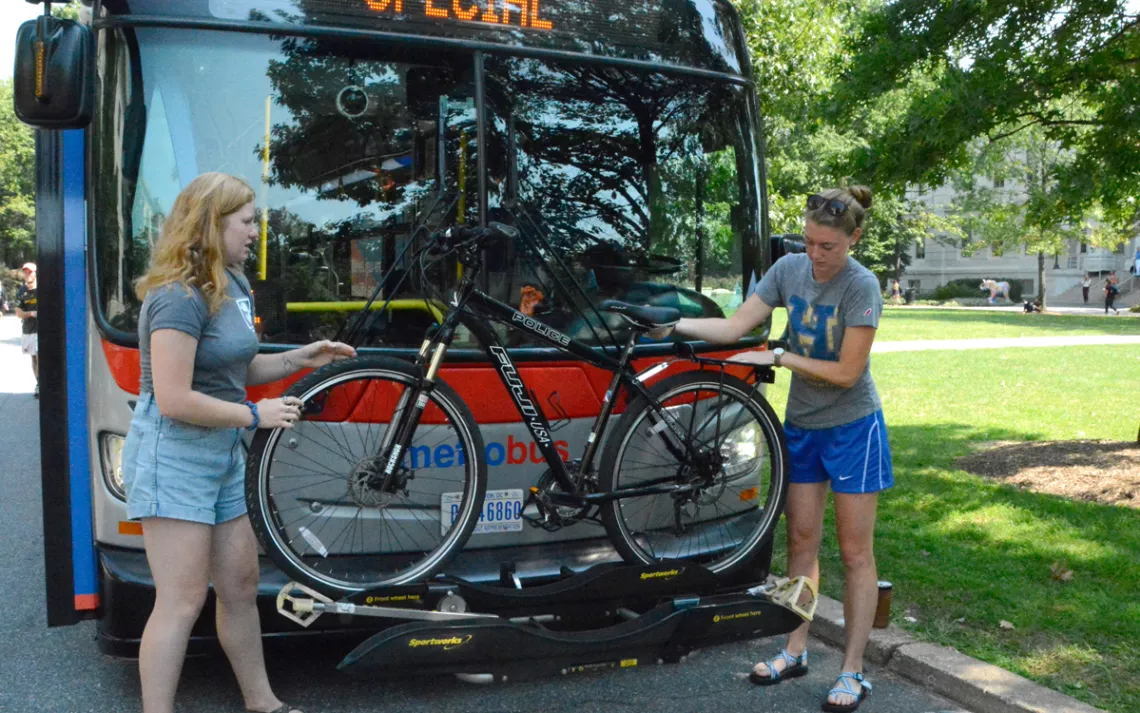 American University emphasizes the importance of alternate transportation during its annual Transportation Fair.  Here, a student sustainability educator demonstrates how to put a bike on the front of a bus.