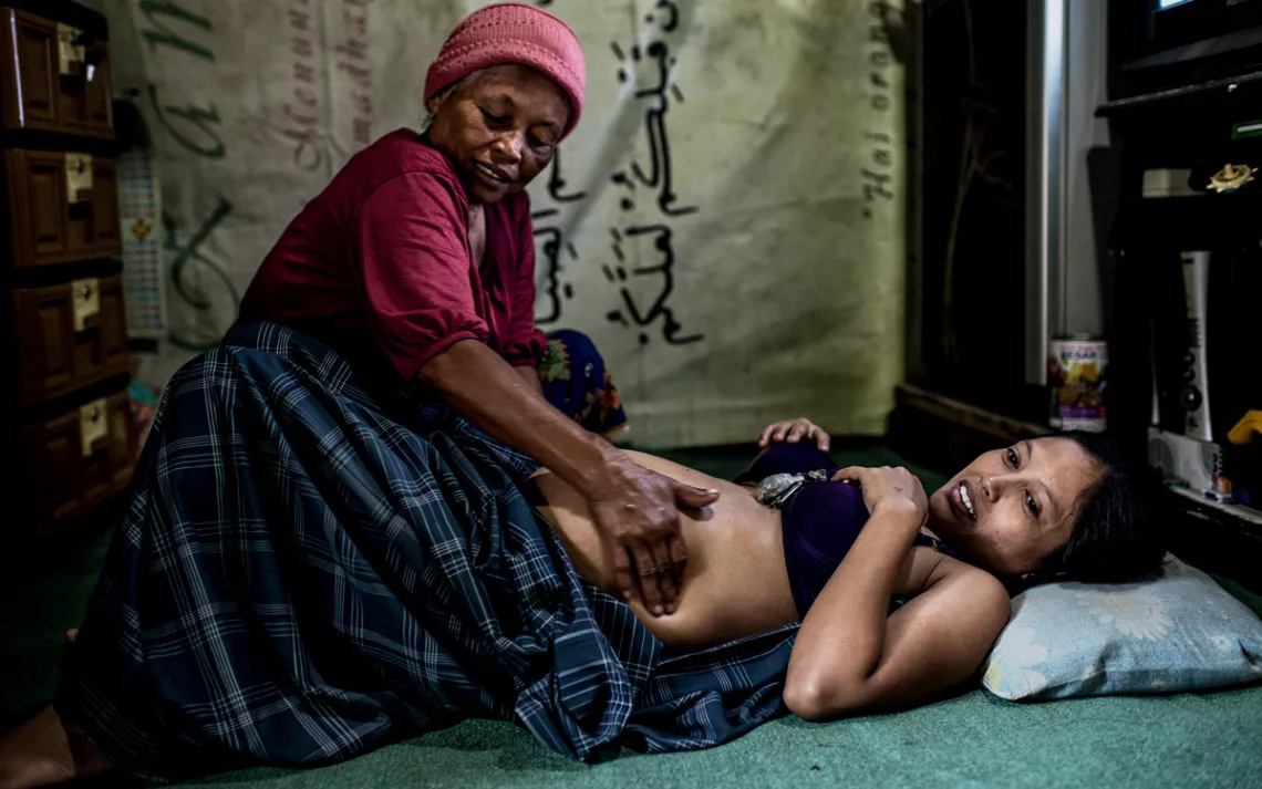 Muji visits her neighbor, who is seven months' pregnant, and checks to see if the baby is in the right position for birth.
