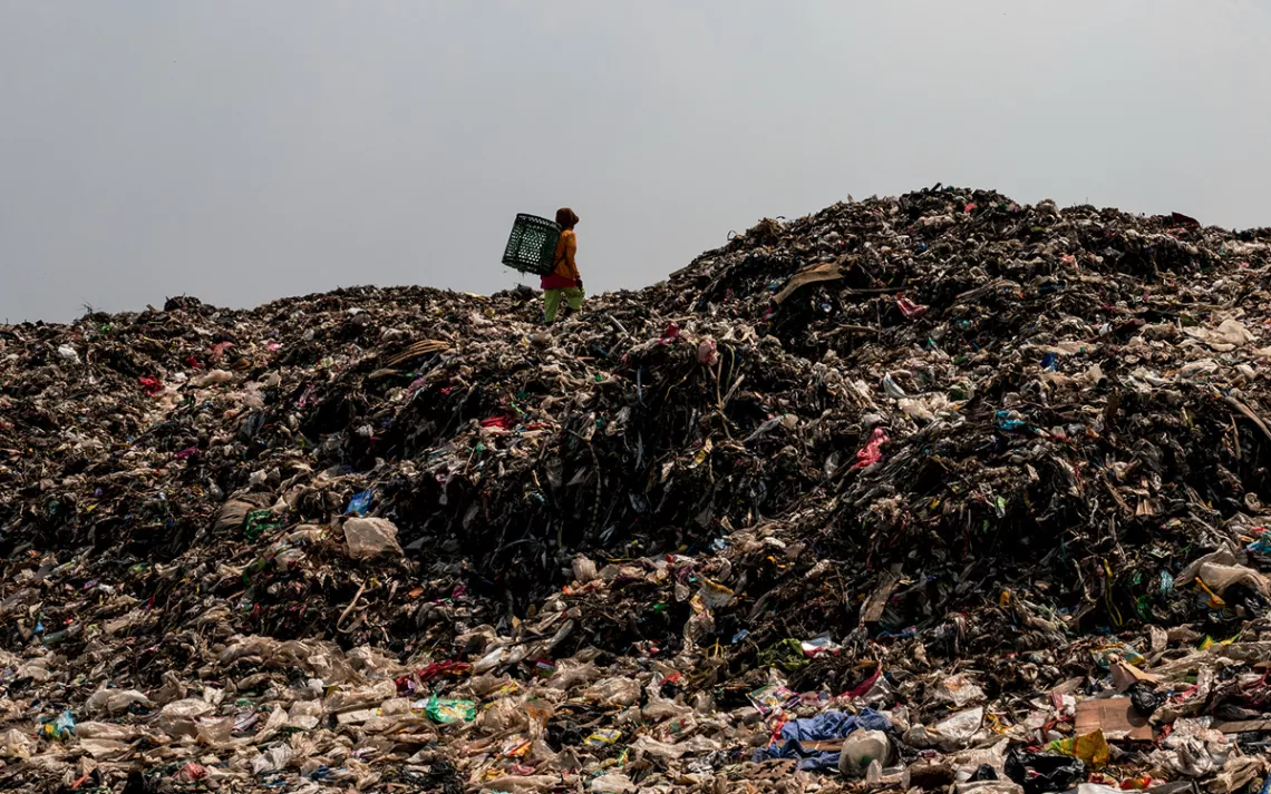 Muji climbs up a mountain of garbage at Bantar Gebang. She collects plastics, glass, cans, shoes, and iron to sell to recycling factories.