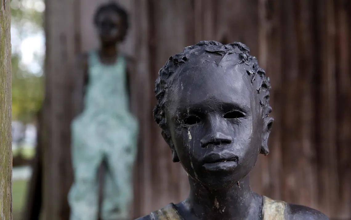 This July 14, 2017 photo shows two of the 40 statues spread throughout the grounds, titled "Children of Whitney" by Woodrow Nash, in front of one of the slave cabins at the Whitney Plantation in Edgard, La.