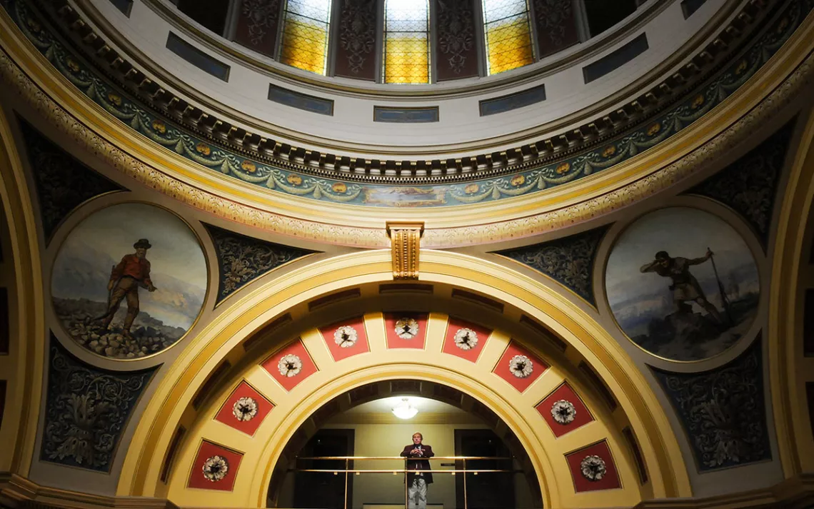 A Sargent of Arms pauses on the fourth floor of the Montana State Capitol overlooking the Rotunda.