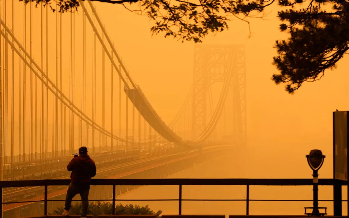 A Man talks on his phone as he looks through the haze at the George Washington Bridge from Fort Lee, N.J., Wednesday, June 7, 2023.