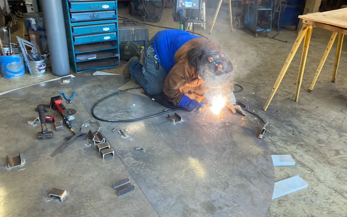 Lummi artist Cyaltsa Finkbonner does some welding touch - ups on her piece. | Photo by Jason Mark