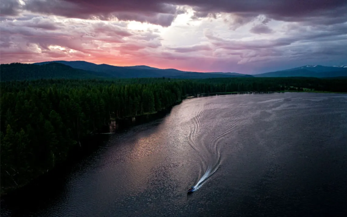 Sunrise or sunset aerial photo of a reservoir with a boat and its wake