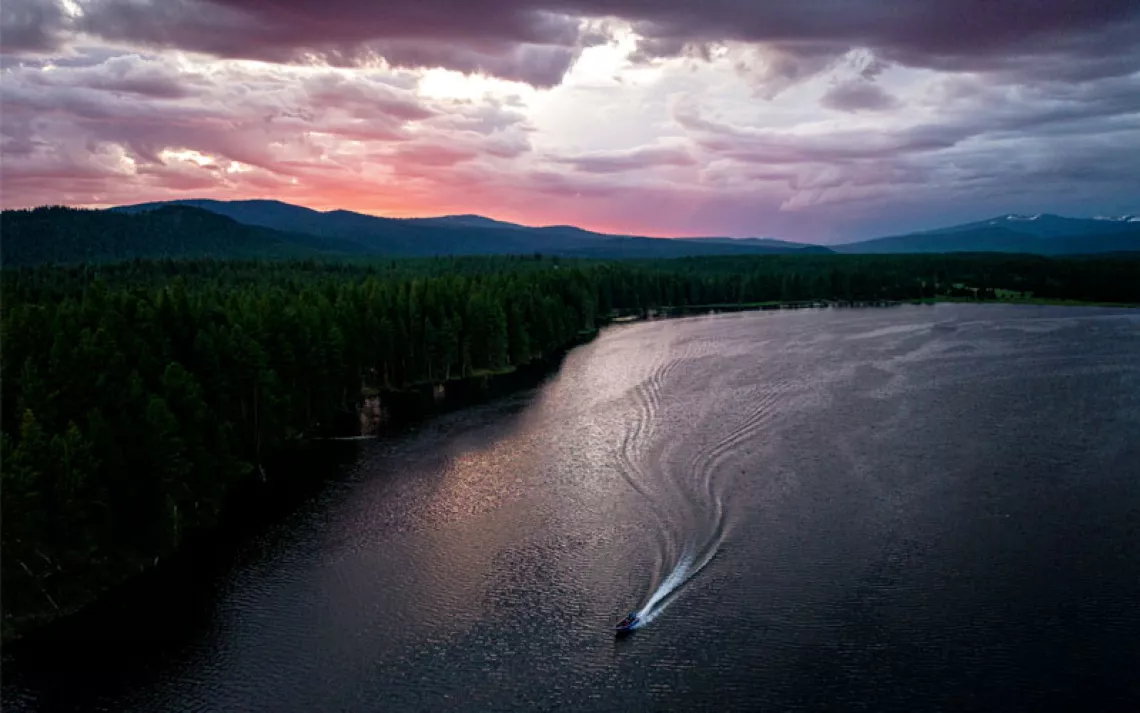 Sunrise or sunset aerial photo of a reservoir with a boat and its wake
