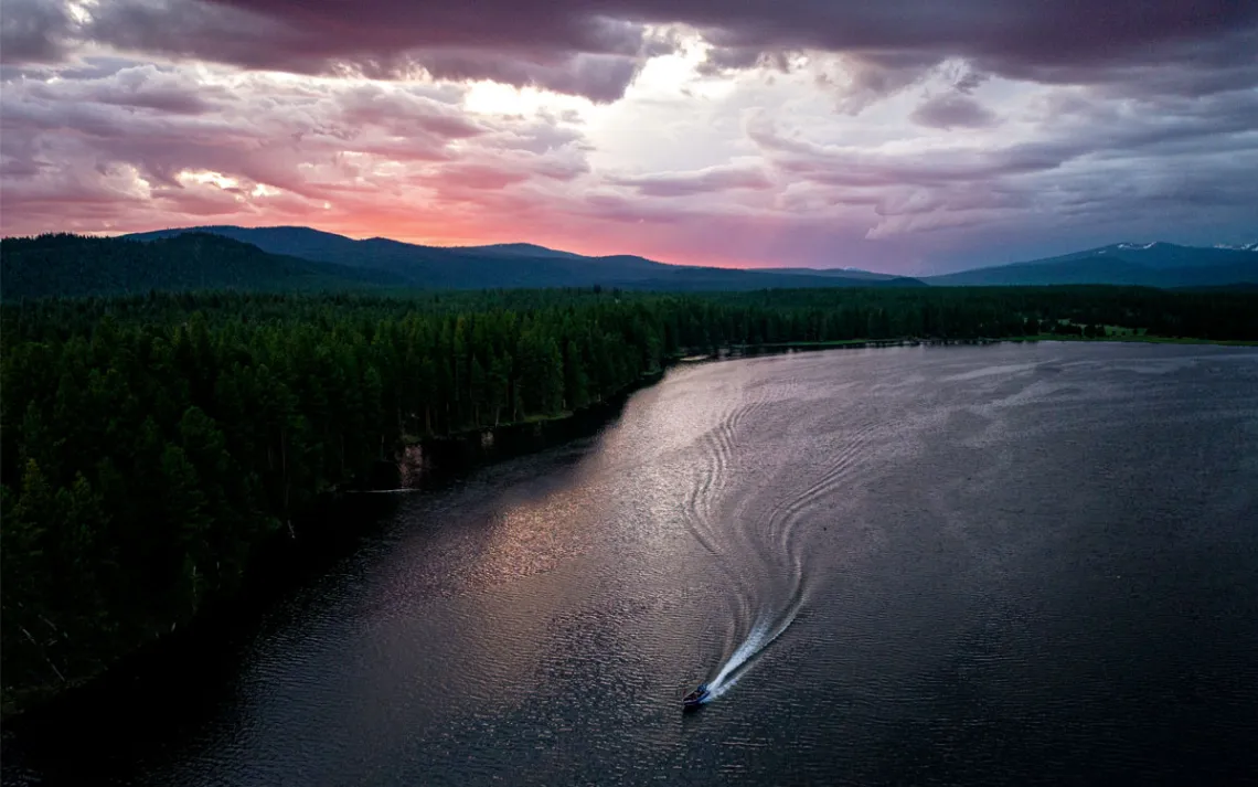 Sunrise or sunset aerial photo of a reservoir with a boat and its wake