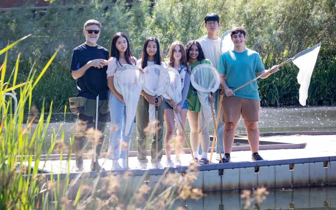 Dick Jordan stands with six students holding nets on a boat dock.