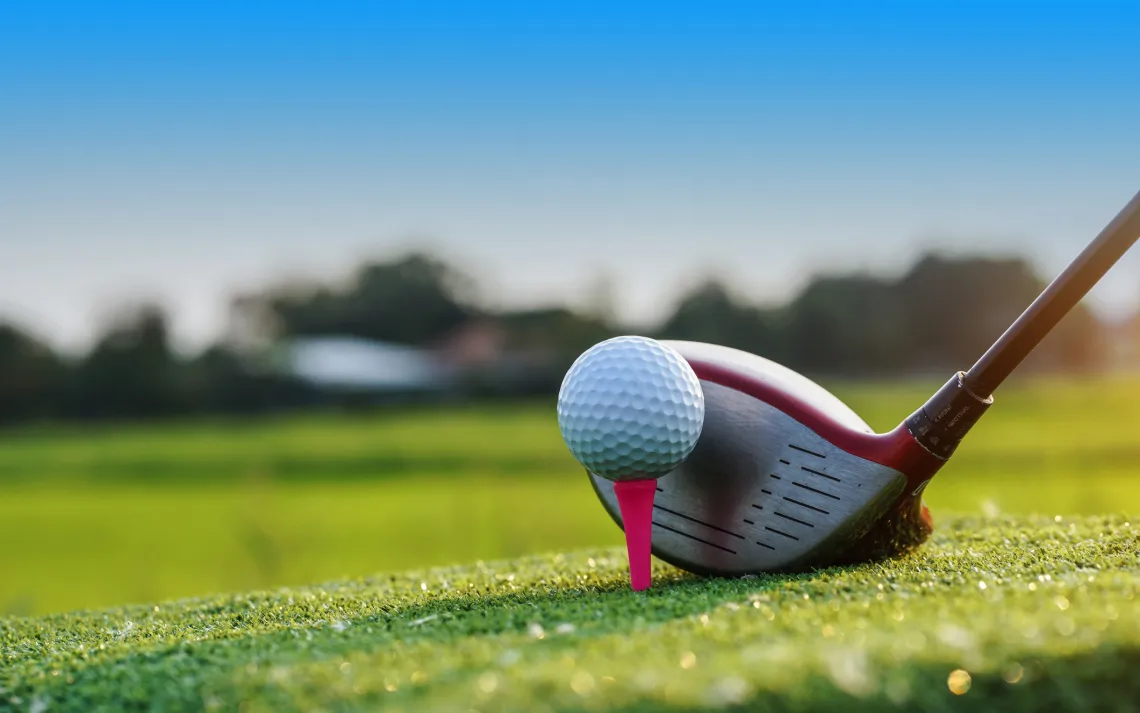 golf club in front of a golf ball on a tee