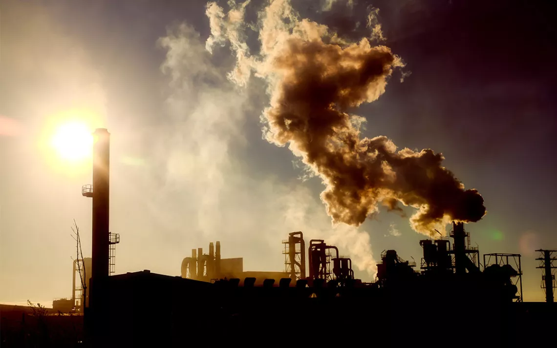 Smoking chimney at sunset on industrial buildings complex