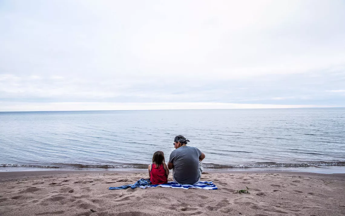 Father and son sitting at Waverley Beach on the shores of Lake Superior