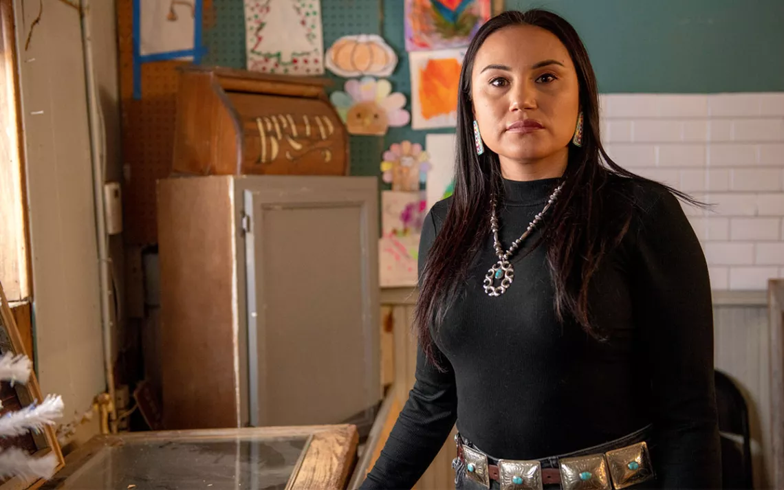 Tana Cummins stands in a coffee shop wearing a black sweater and silver and turquoise jewelry